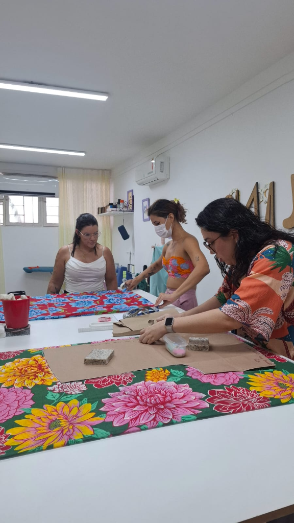Alunas no ateliê Costuralle praticando corte e modelagem na bancada